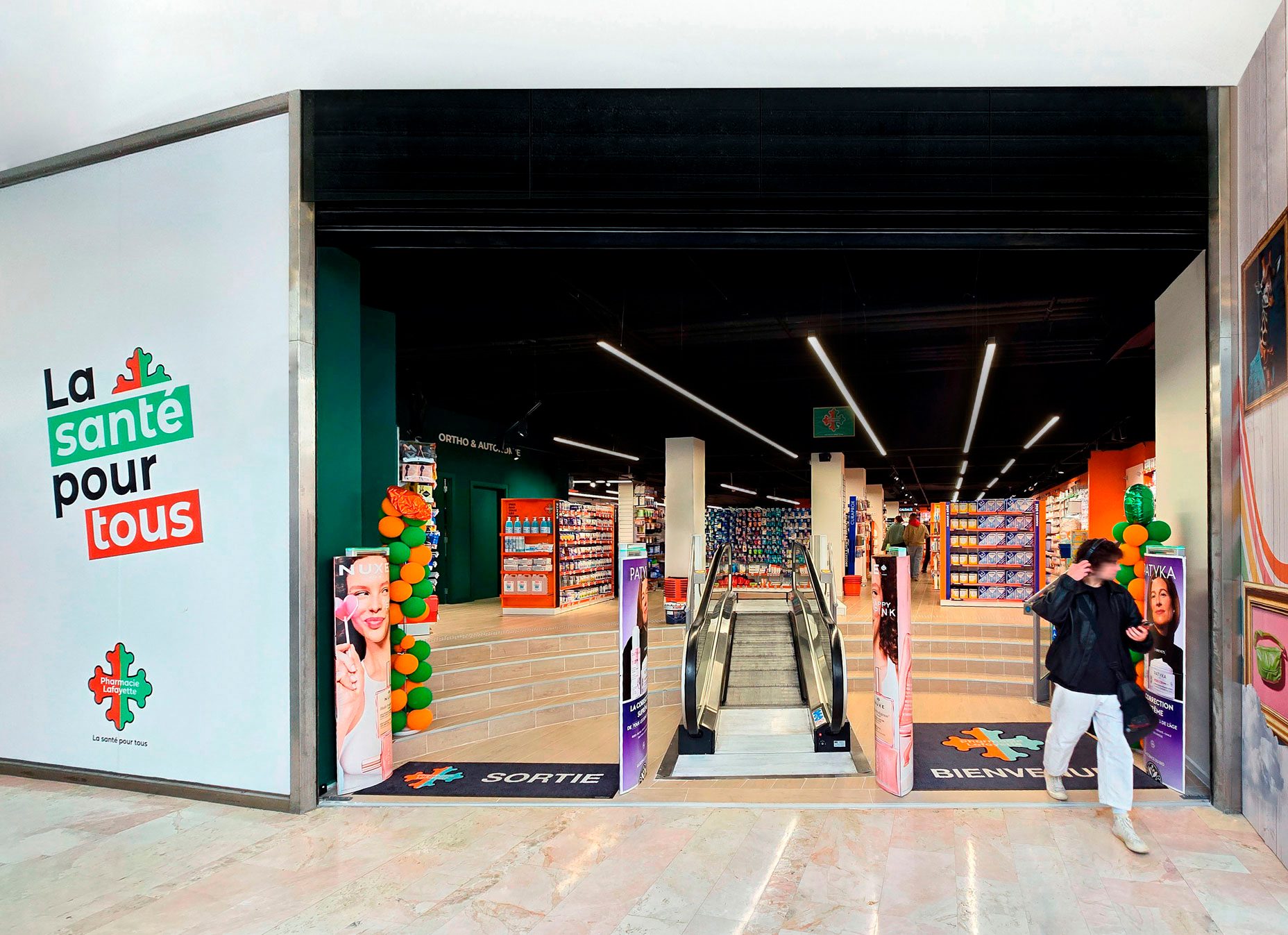 Pharmacie Colombia Lafayette – Medd Agencement Entrée de la Pharmacie Colombia Lafayette avec tapis d’accueil personnalisé au nom du groupe et éclairage soigné, aménagement par Medd Agencement.