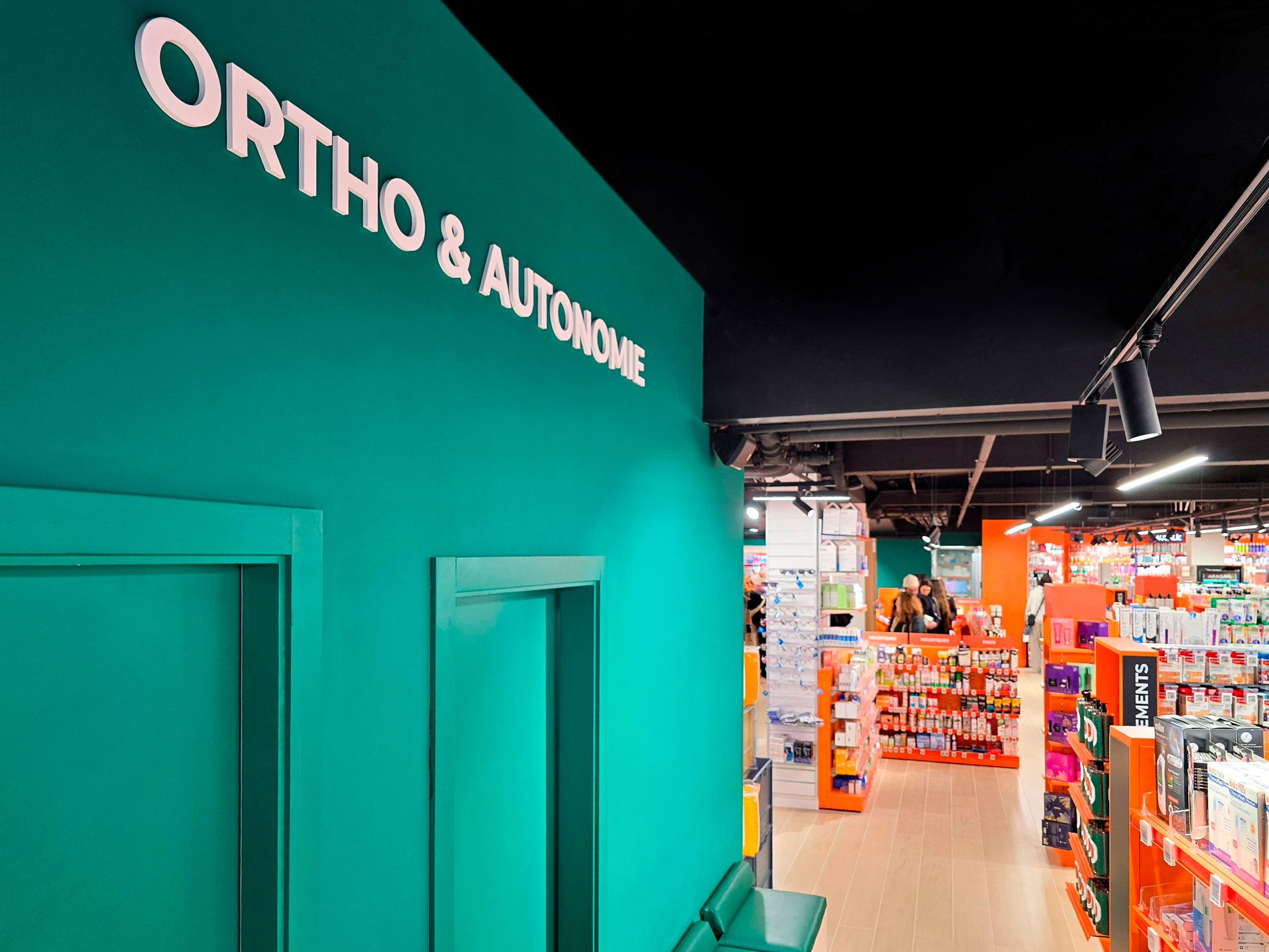 Pharmacie Colombia Lafayette – Medd Agencement Zone d’orthopédie à la Pharmacie Colombia Lafayette avec mur bleu-vert apaisant et espace d’exposition lumineux, design par Medd Agencement.