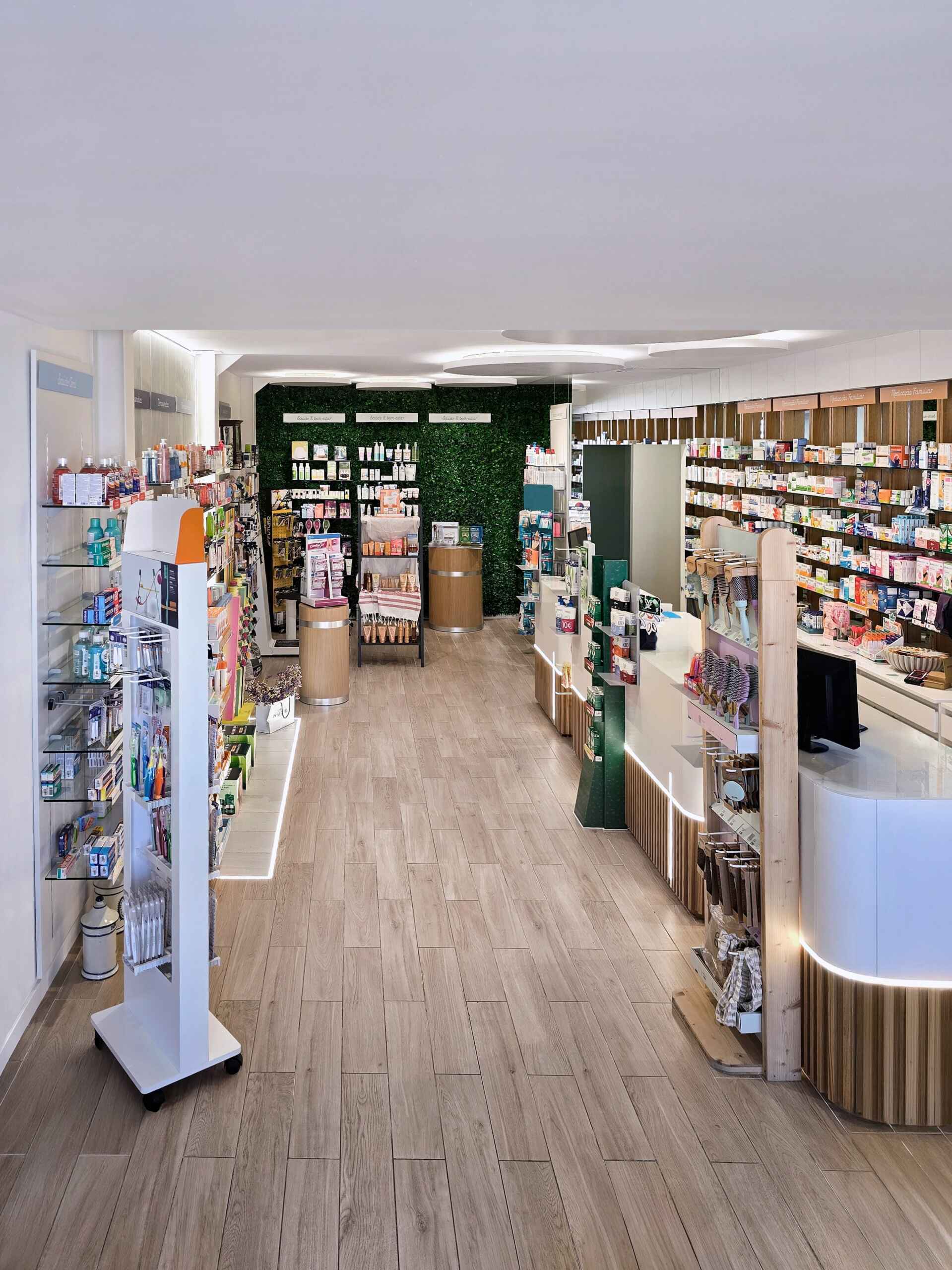 Farmácia Batista Coimbra – Medd Design Visão geral do interior moderno e funcional da Farmácia Batista Coimbra, com layout organizado e mobiliário técnico em madeira clara, projeto Medd Design.